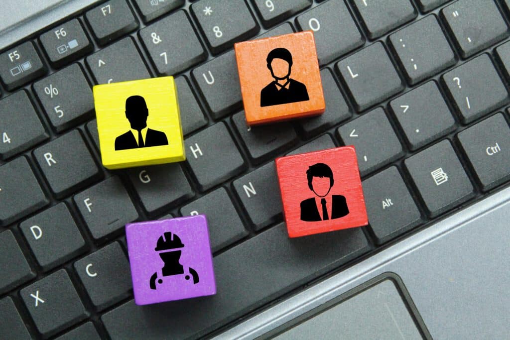 Bunte Figuren, die Fachkräfte und Geschäftsführer symbolisieren, liegen auf dem Laptop, um zu zeigen, dass sie wichtige Faktoren sind für ein Unternehmen.